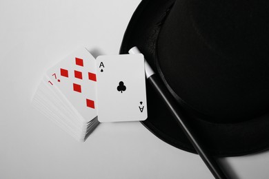 Photo of Playing cards, hat and magic wand on light background, closeup