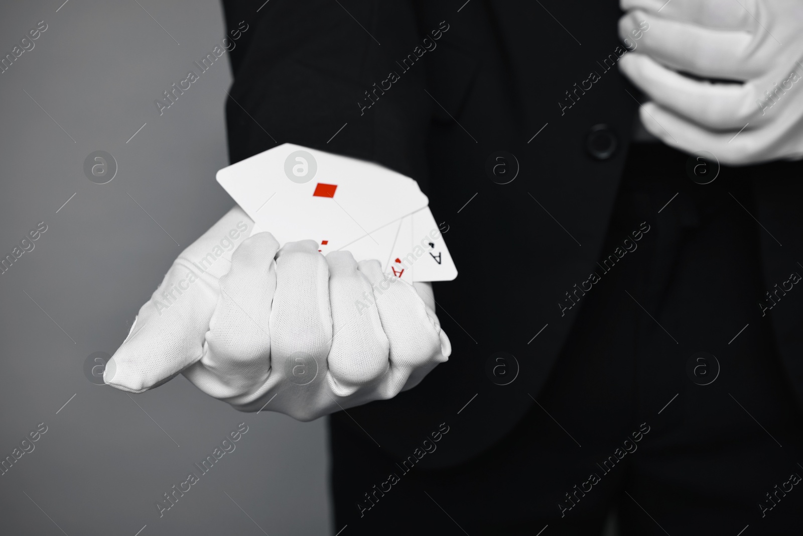 Photo of Illusionist taking playing cards out of sleeve on grey background, closeup