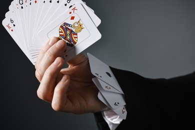 Photo of Illusionist with playing cards on grey background, closeup