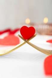 Romantic table setting for Valentine's day. Decorative heart between forks on white plate, closeup