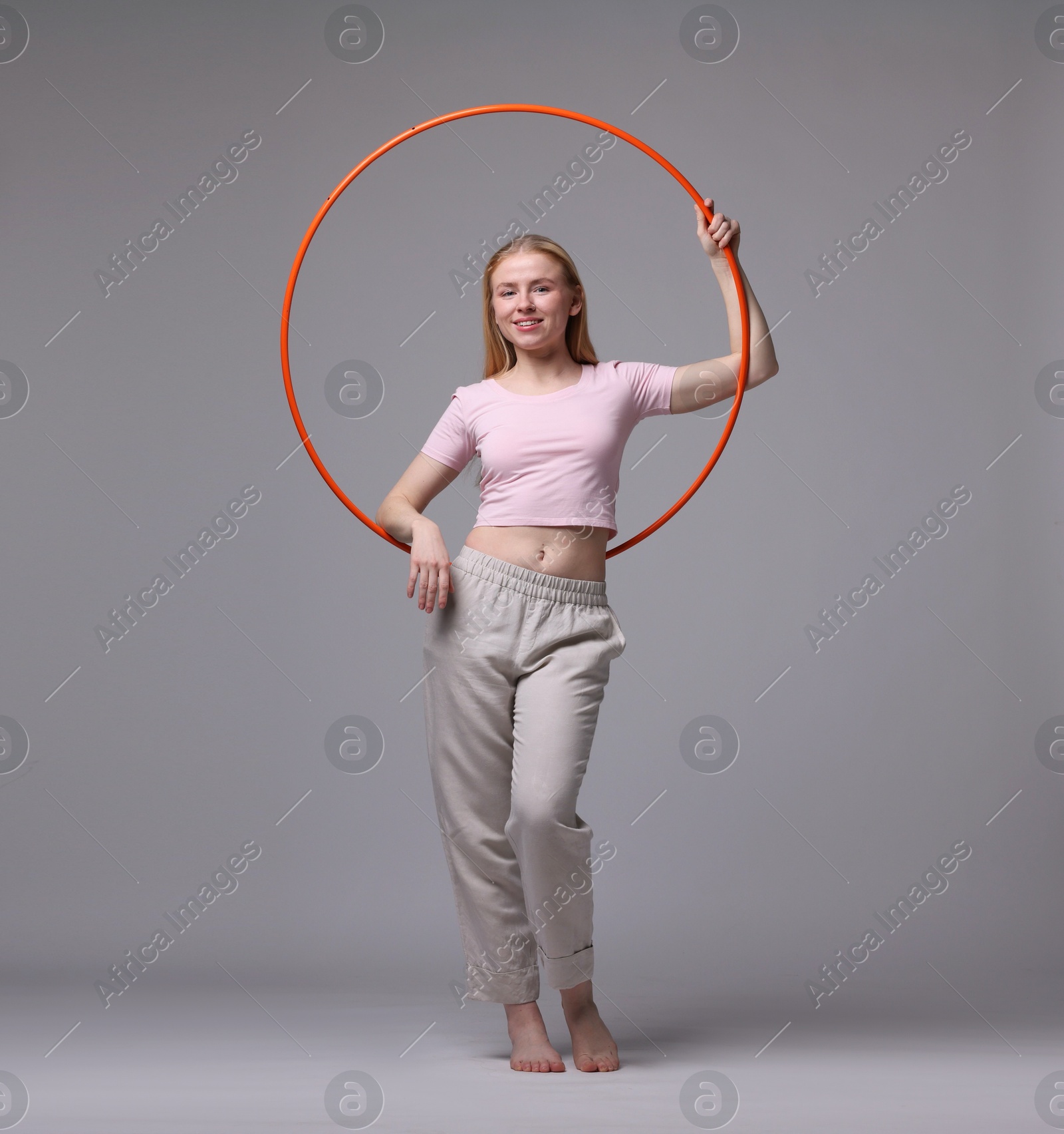 Photo of Beautiful young woman with hula hoop on grey background