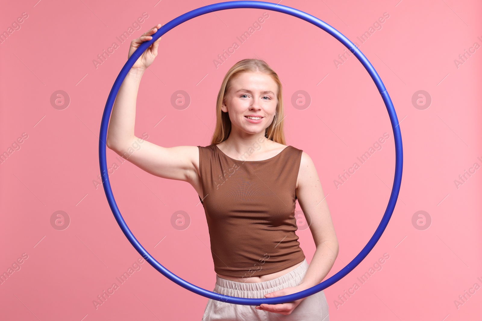 Photo of Beautiful young woman with hula hoop on pink background