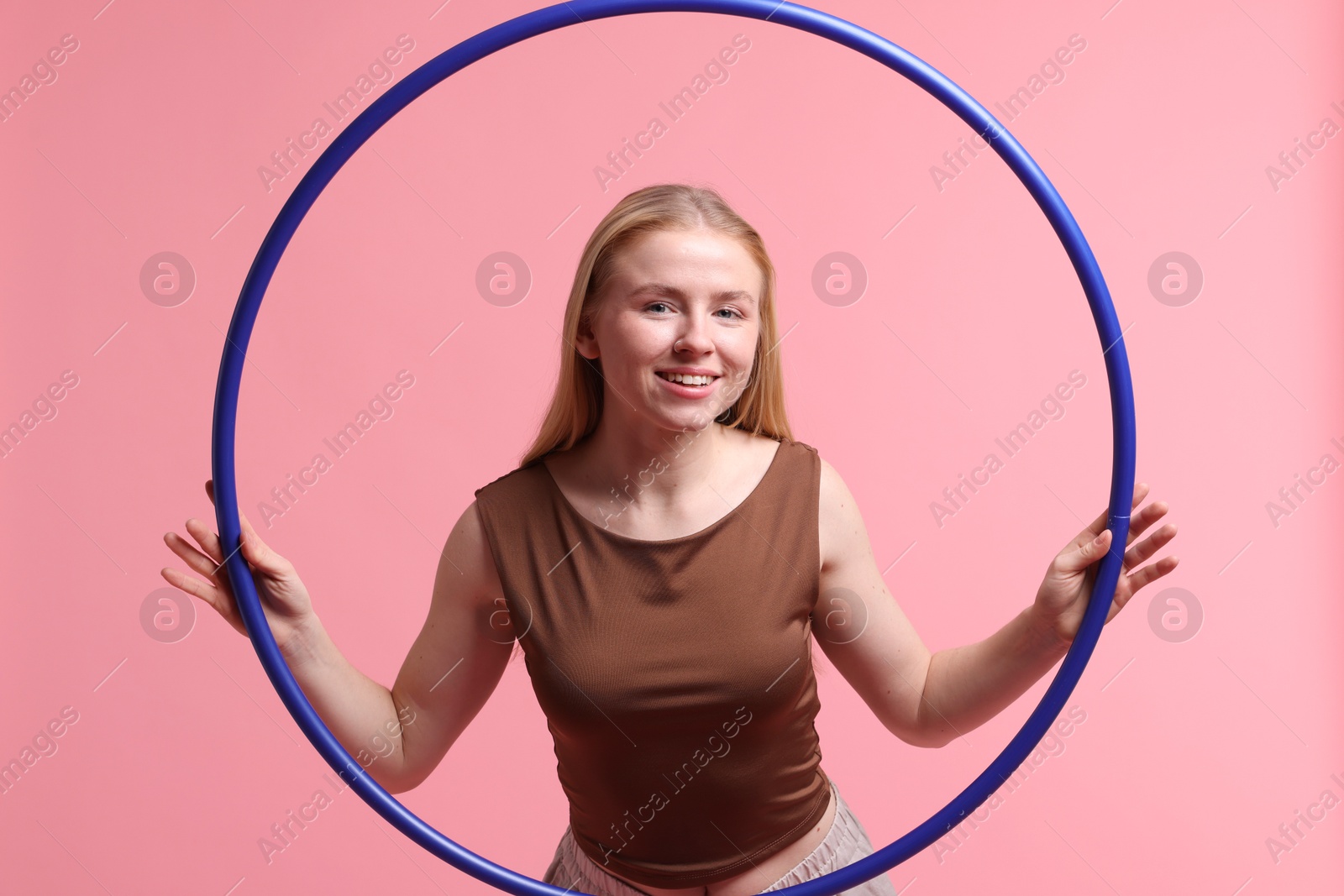 Photo of Beautiful young woman with hula hoop on pink background