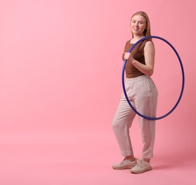 Beautiful young woman with hula hoop on pink background, space for text