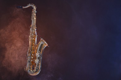 Golden saxophone on dark background with smoke. Space for text