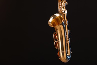 Golden saxophone on black background, closeup. Space for text