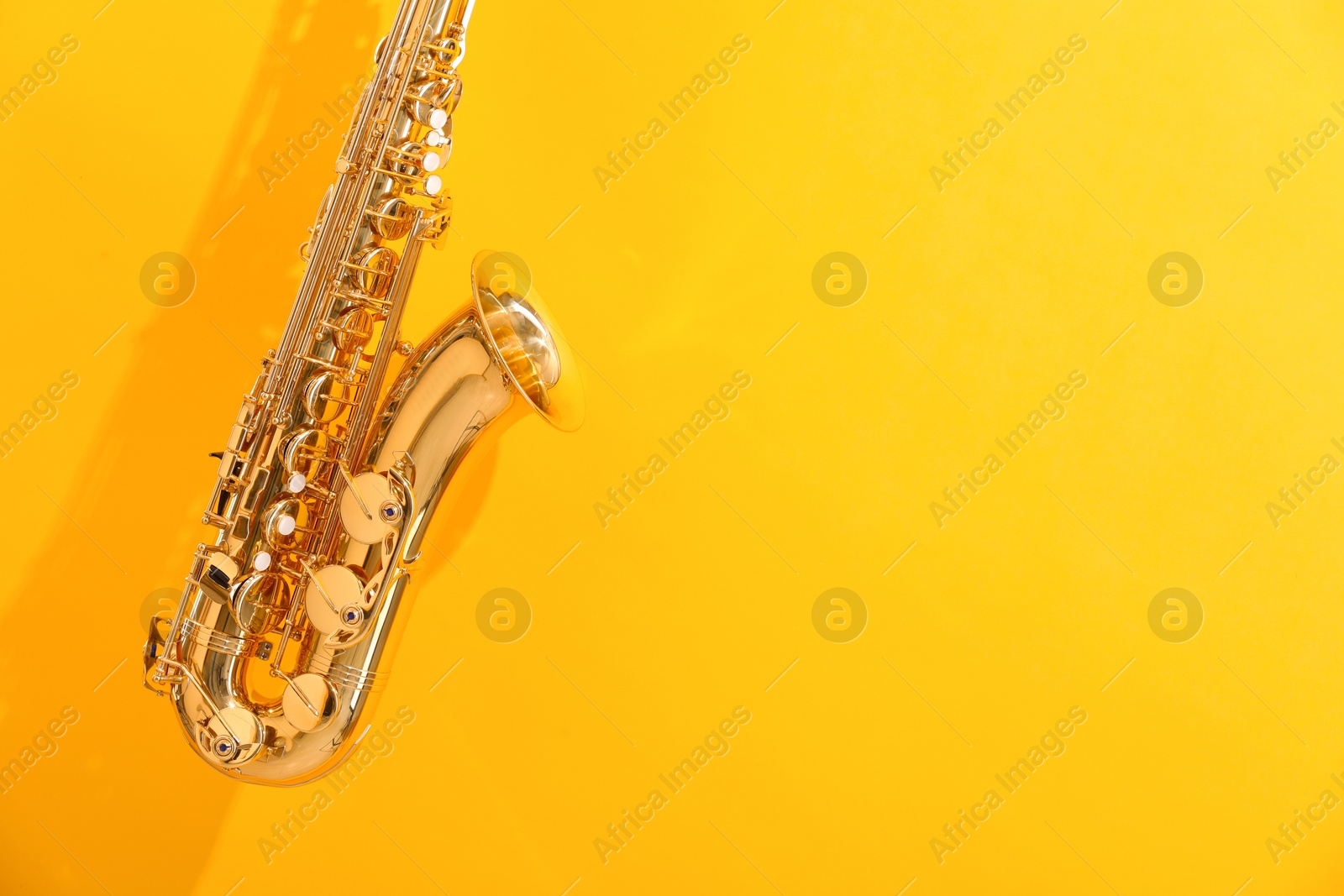 Photo of Golden saxophone on yellow background. Space for text