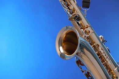 Photo of Golden saxophone on blue background, closeup. Space for text