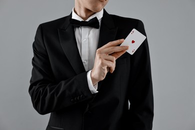 Illusionist showing playing card on grey background, closeup