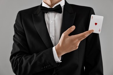 Illusionist showing playing card on grey background, closeup