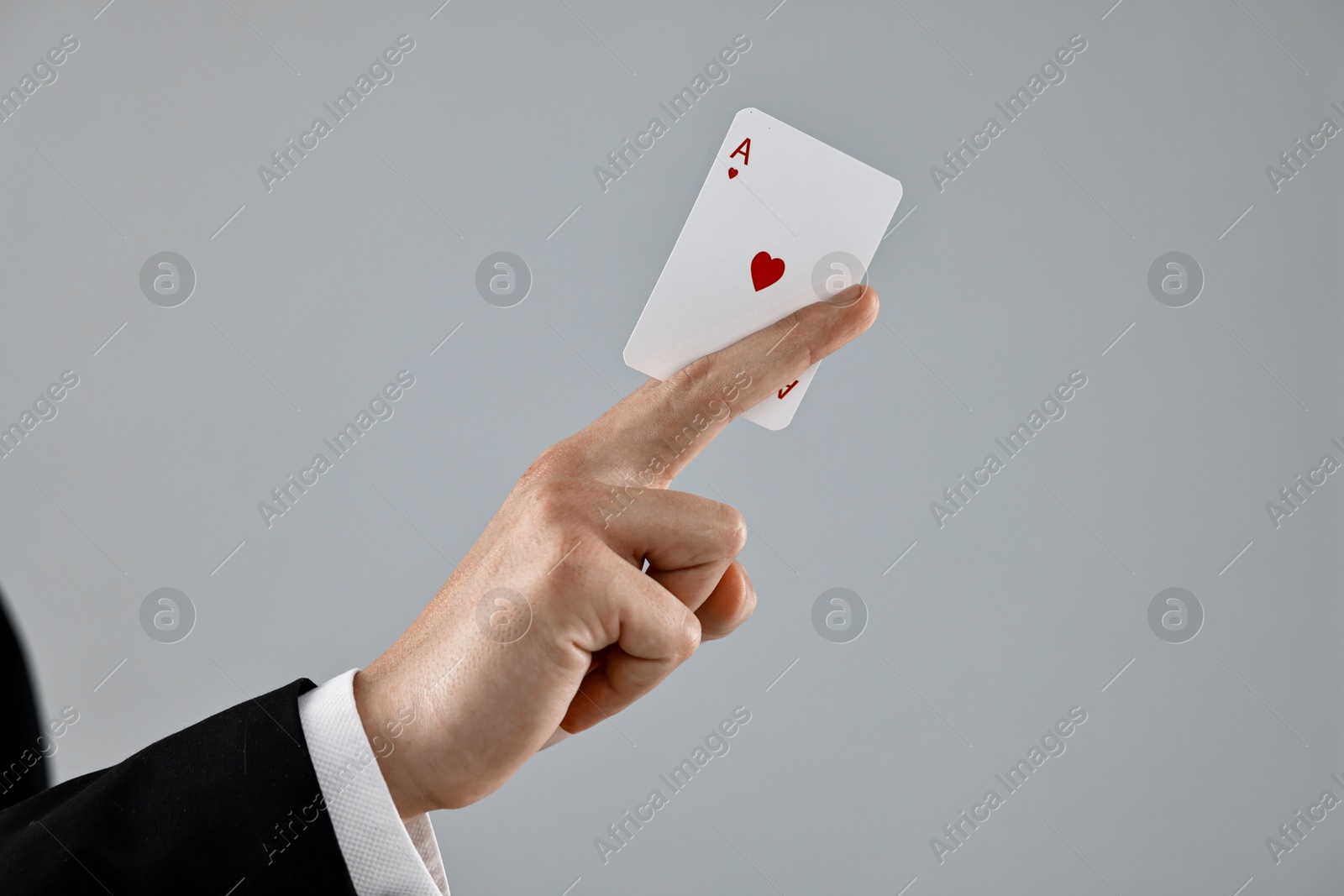 Photo of Illusionist showing playing card on grey background, closeup. Space for text