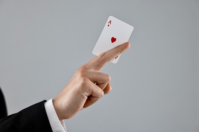 Illusionist showing playing card on grey background, closeup. Space for text