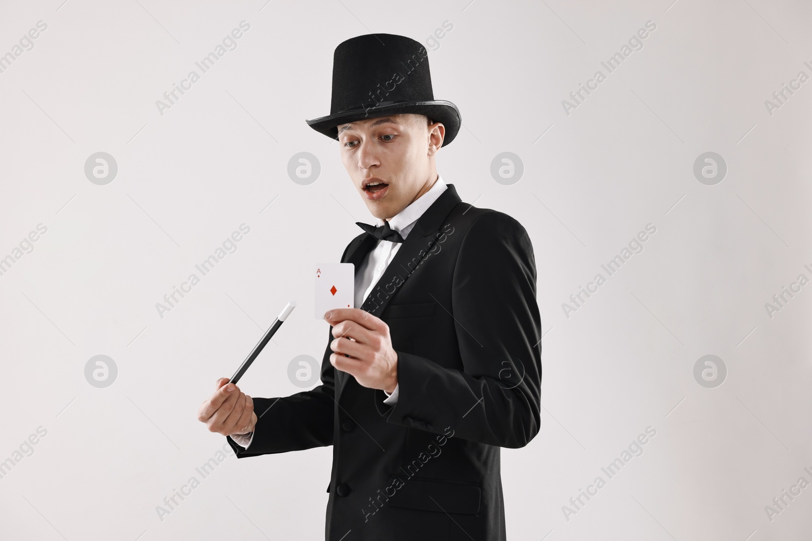 Photo of Illusionist pointing magic wand on playing card against white background