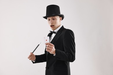 Photo of Illusionist pointing magic wand on playing card against white background