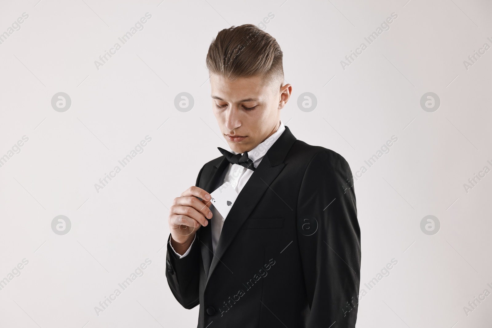 Photo of Illusionist hiding playing card behind jacket lapel on white background