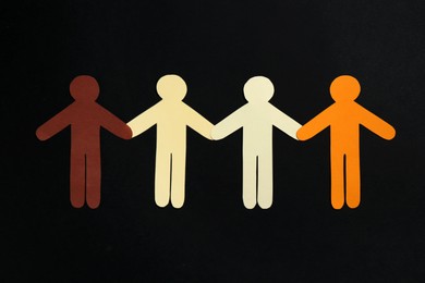 Photo of Stop racism. Human paper figures of different colors on black background, top view