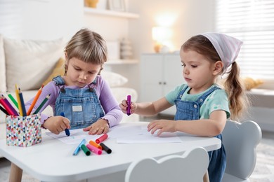 Photo of Cute little sisters drawing at white table in room