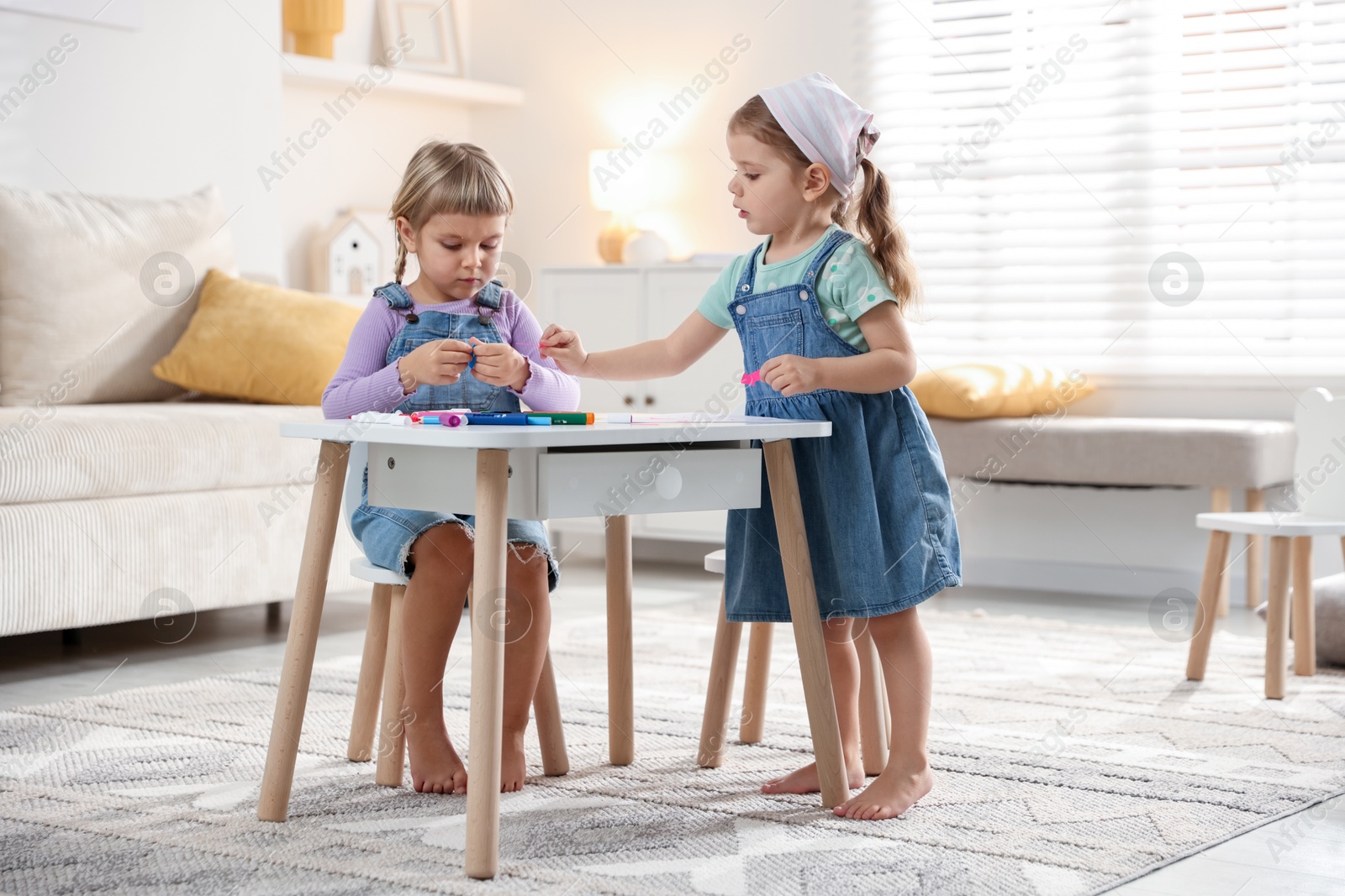 Photo of Cute little sisters drawing at white table in room