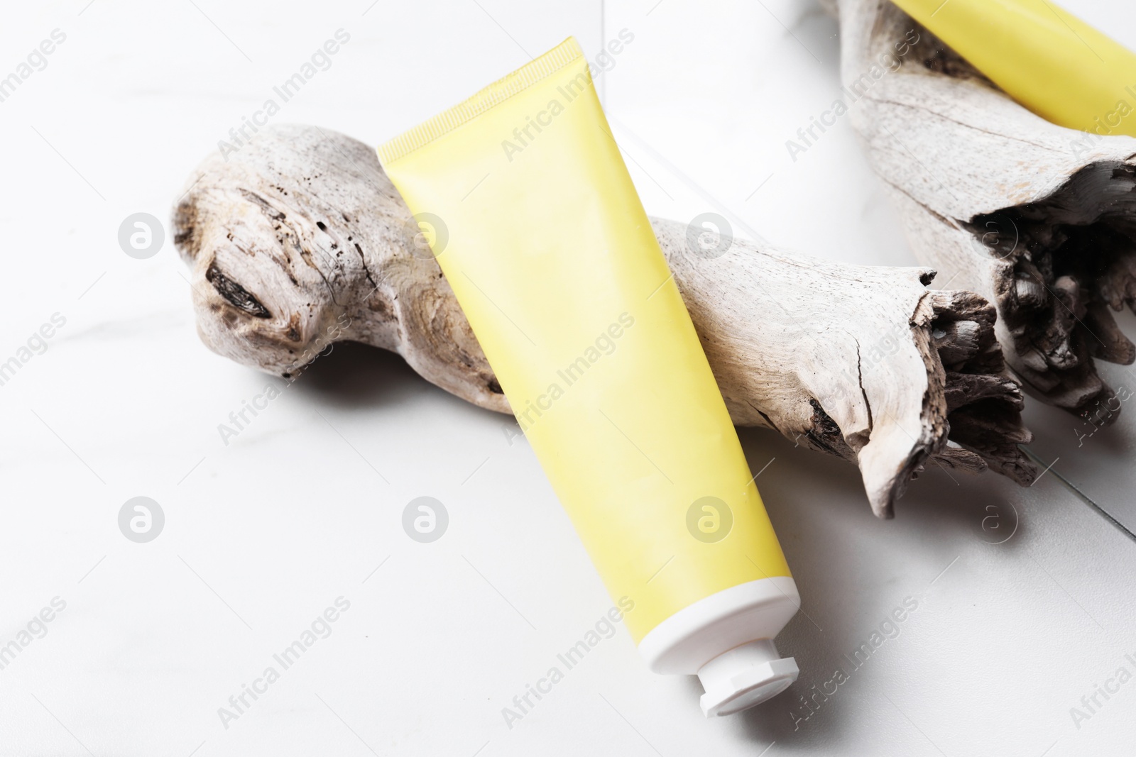 Photo of Tube of cream, snag and mirror on light background, closeup