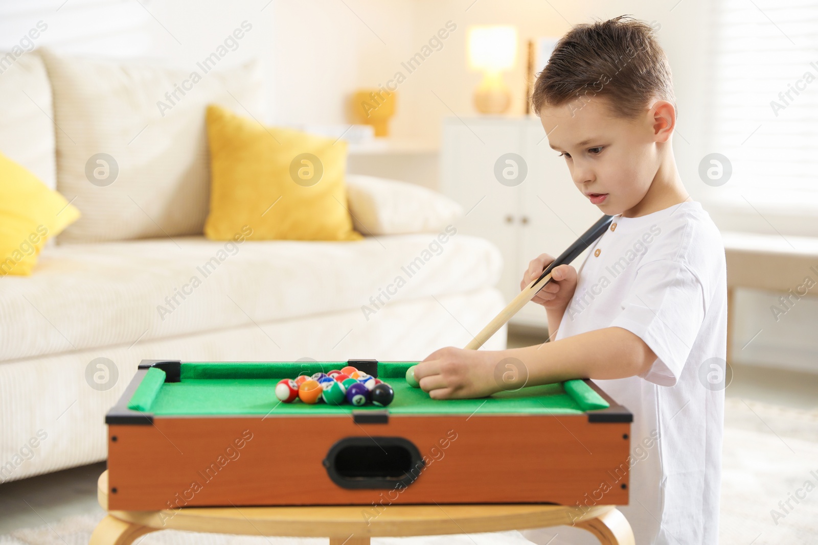 Photo of Cute little boy playing billiards at home