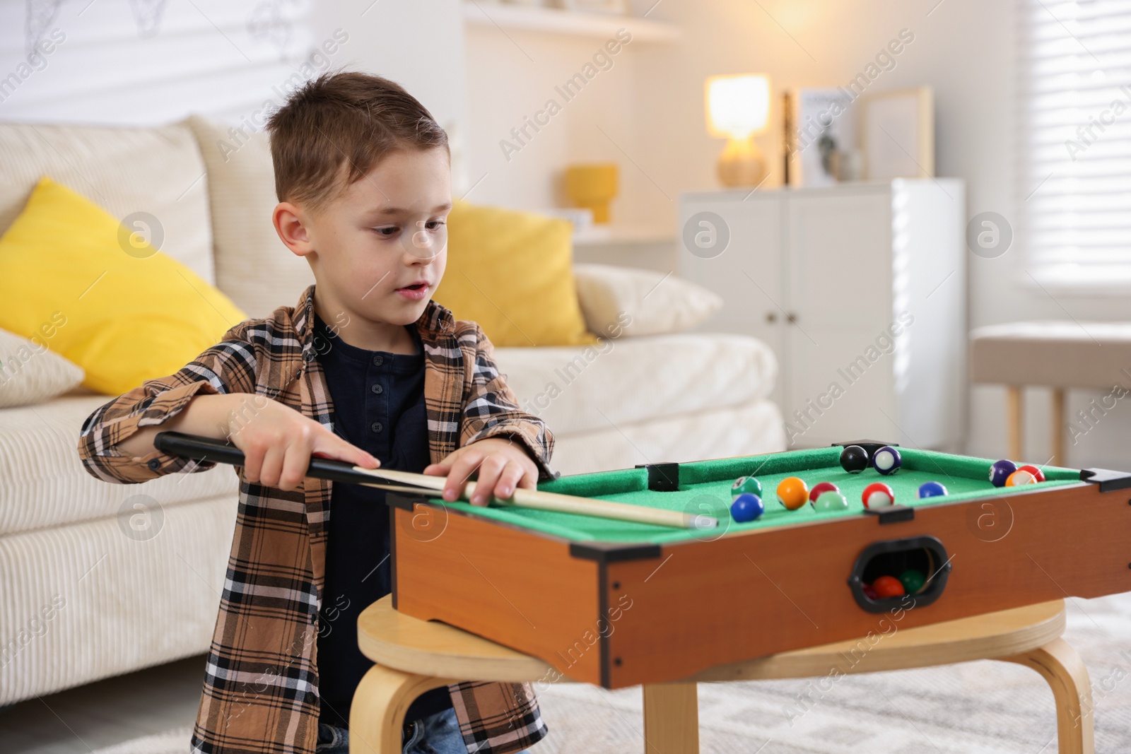 Photo of Cute little boy playing billiards at home