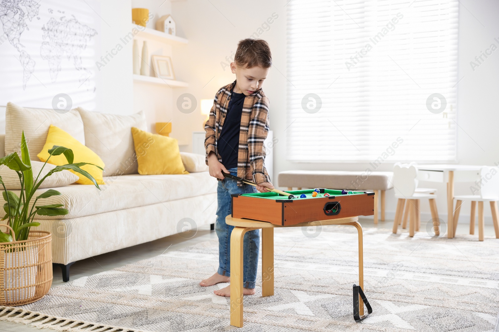 Photo of Cute little boy playing billiards at home