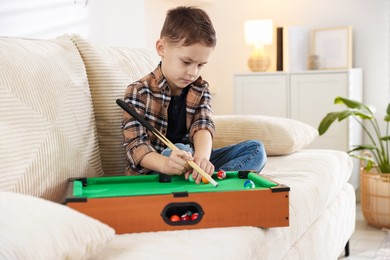 Photo of Cute little boy playing billiards at home