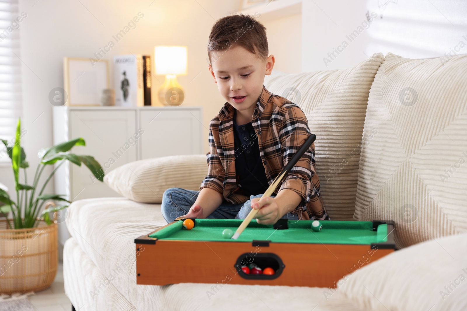 Photo of Cute little boy playing billiards at home