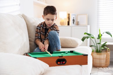 Cute little boy playing billiards at home