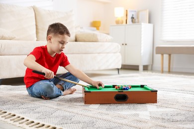 Cute little boy playing billiards at home