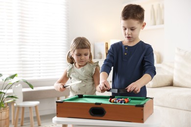 Cute brother and sister playing billiards at home