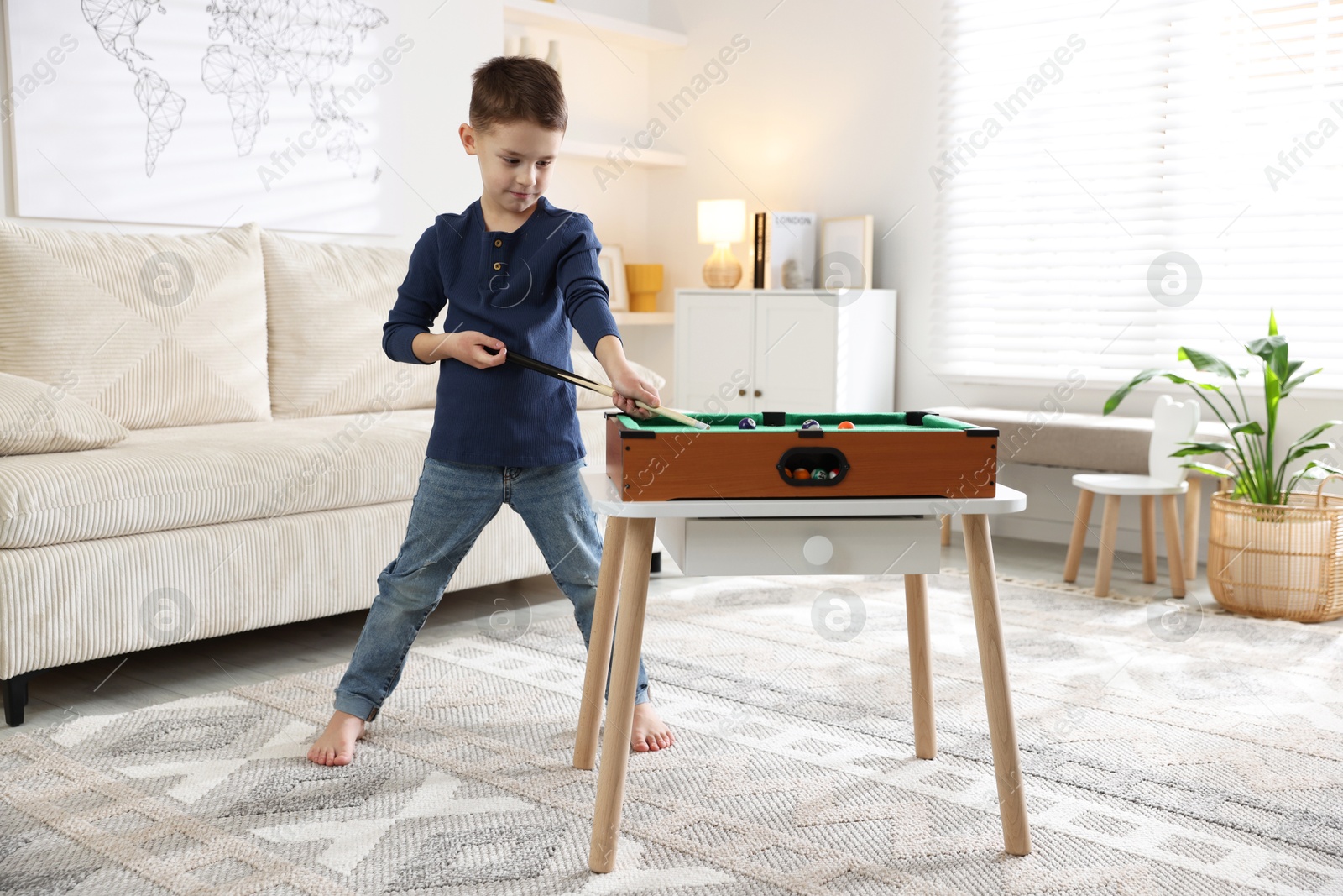 Photo of Cute little boy playing billiards at home