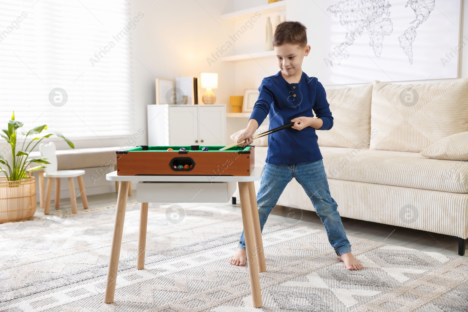 Photo of Cute little boy playing billiards at home