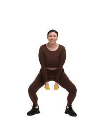 Photo of Plus size woman in gym clothes doing exercise with dumbbells on white background