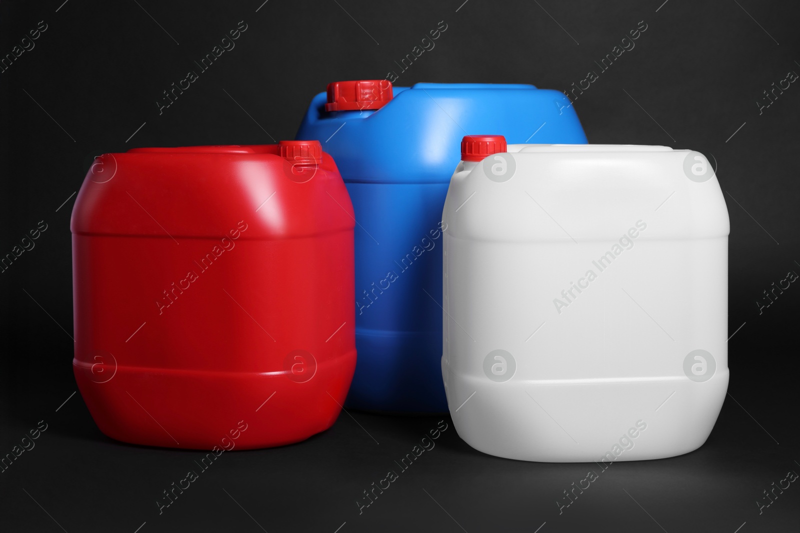 Photo of Three colorful plastic canisters on black background