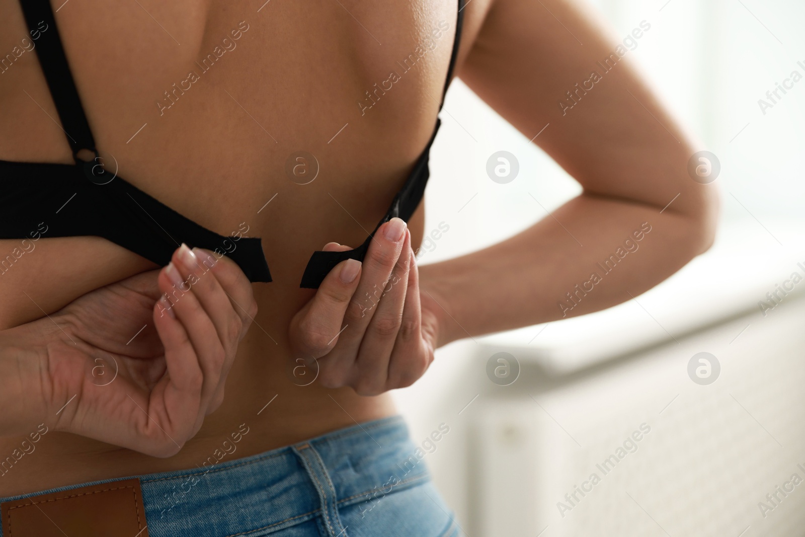 Photo of Woman putting on comfortable bra indoors, closeup