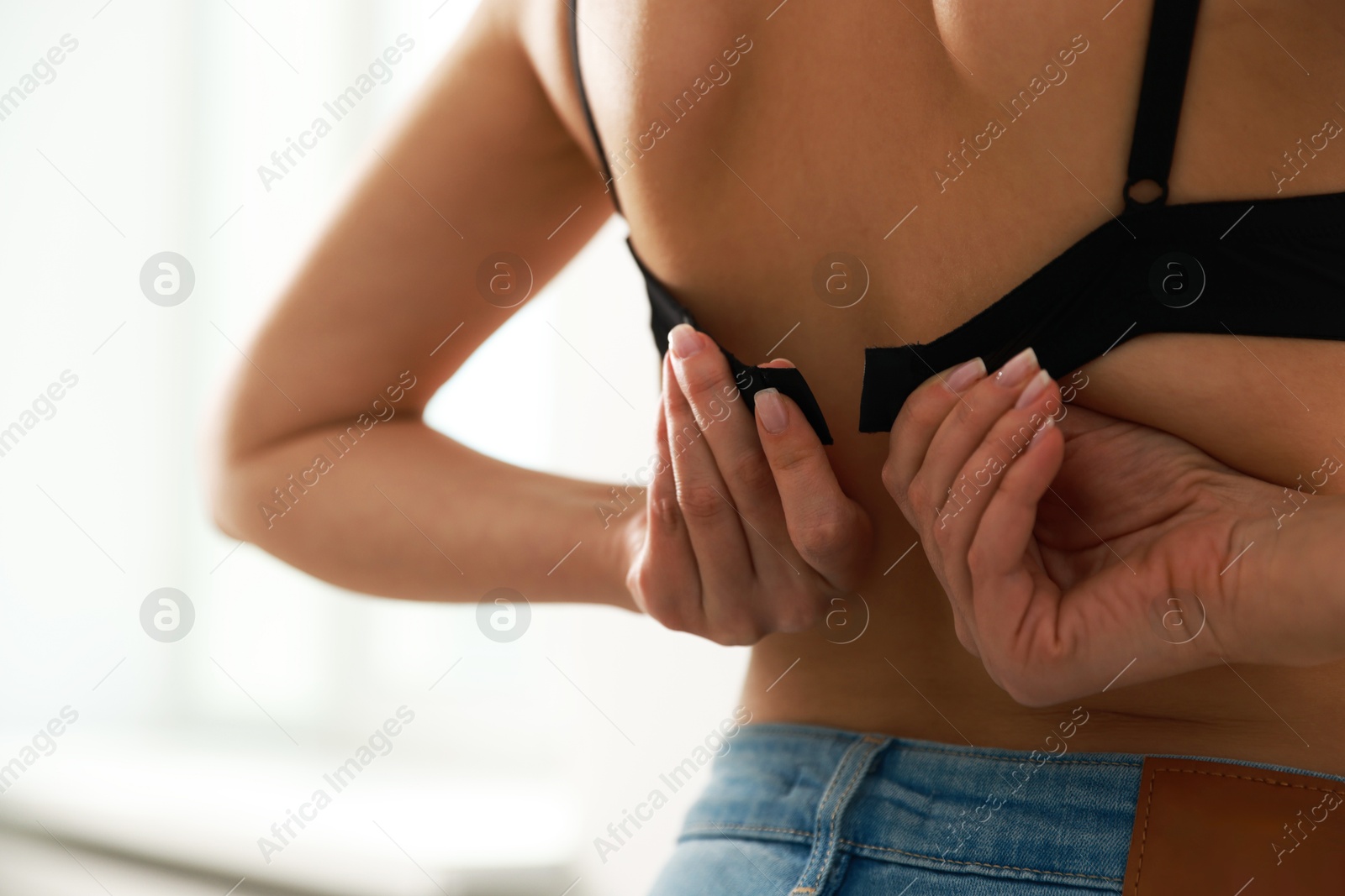 Photo of Woman putting on comfortable bra indoors, closeup