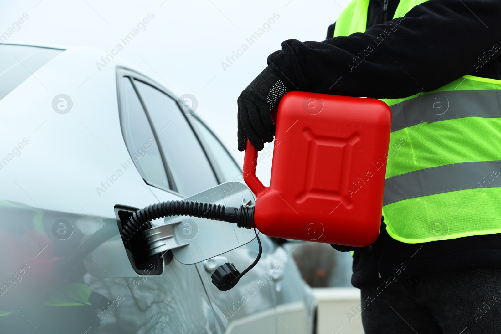 Photo of Man with canister refueling car outdoors, closeup