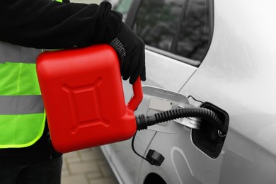 Photo of Man with canister refueling car outdoors, closeup