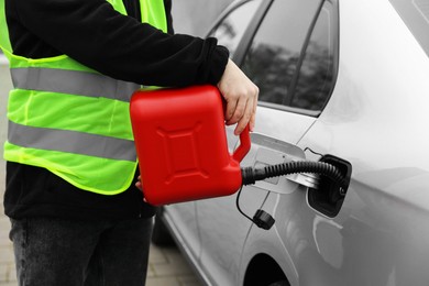 Photo of Man with canister refueling car outdoors, closeup