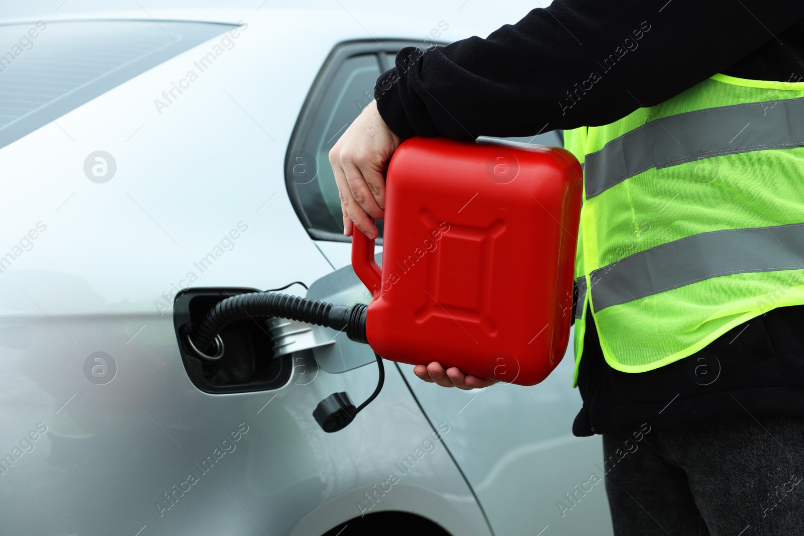 Photo of Man with canister refueling car outdoors, closeup