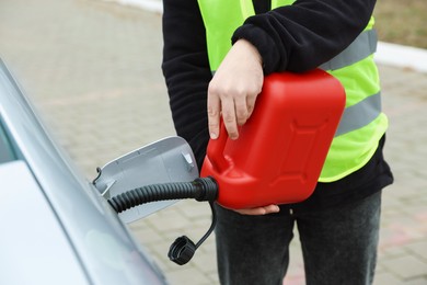 Photo of Man with canister refueling car outdoors, closeup