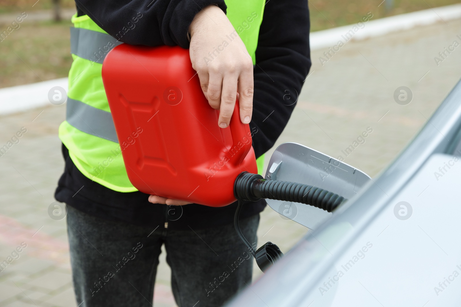 Photo of Man with canister refueling car outdoors, closeup