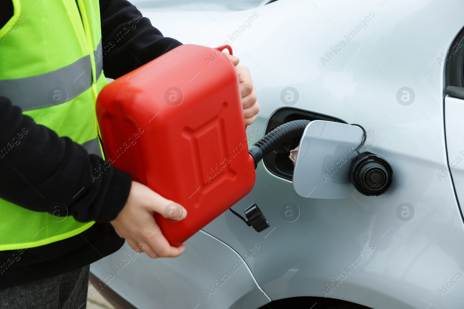 Photo of Man with canister refueling car outdoors, closeup