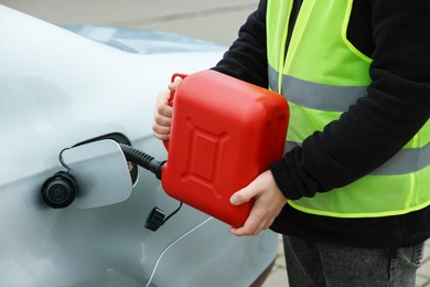 Photo of Man with canister refueling car outdoors, closeup