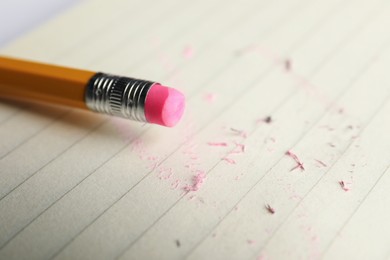 Photo of Pencil with eraser and scraps on sheet of paper, closeup