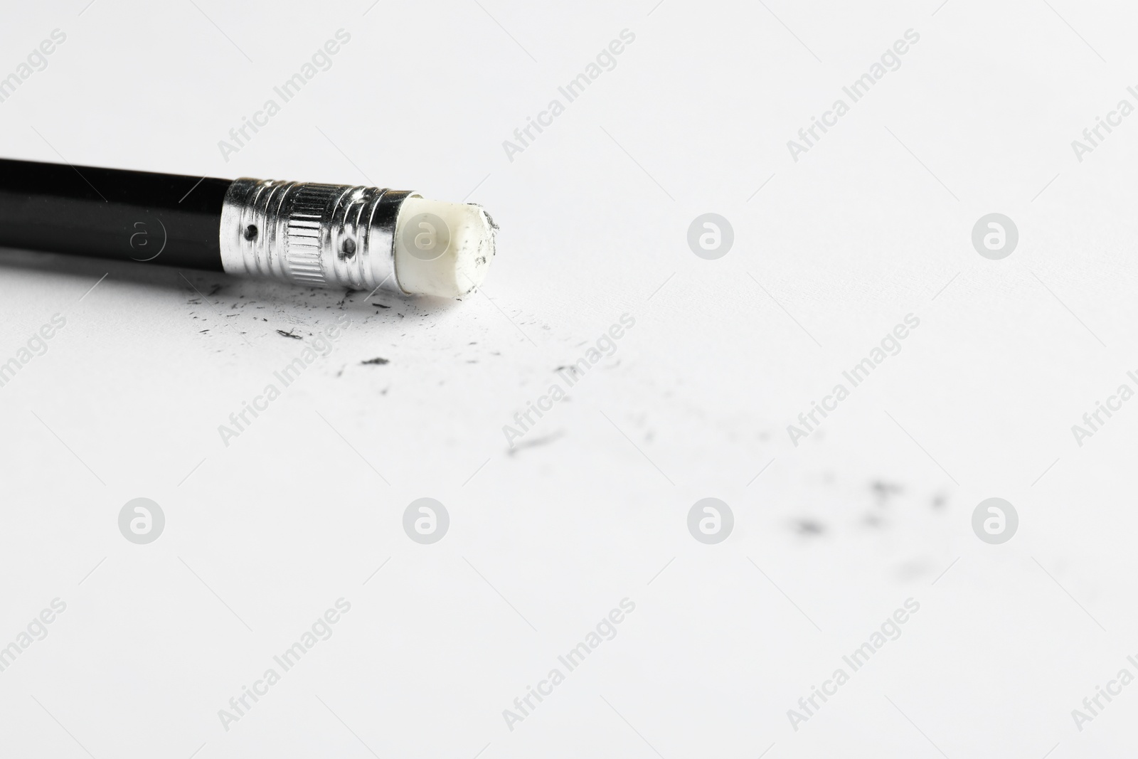 Pencil with eraser and scraps on white sheet of paper, closeup Photo of Pencil with eraser and scraps on white sheet of paper, closeup