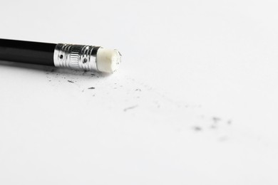 Photo of Pencil with eraser and scraps on white sheet of paper, closeup
