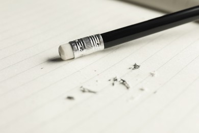 Photo of Pencil with eraser and scraps on sheet of paper, closeup
