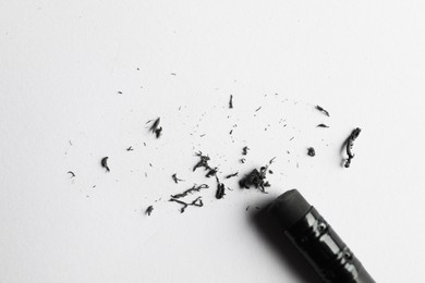 Photo of Pencil with eraser and scraps on white sheet of paper, top view